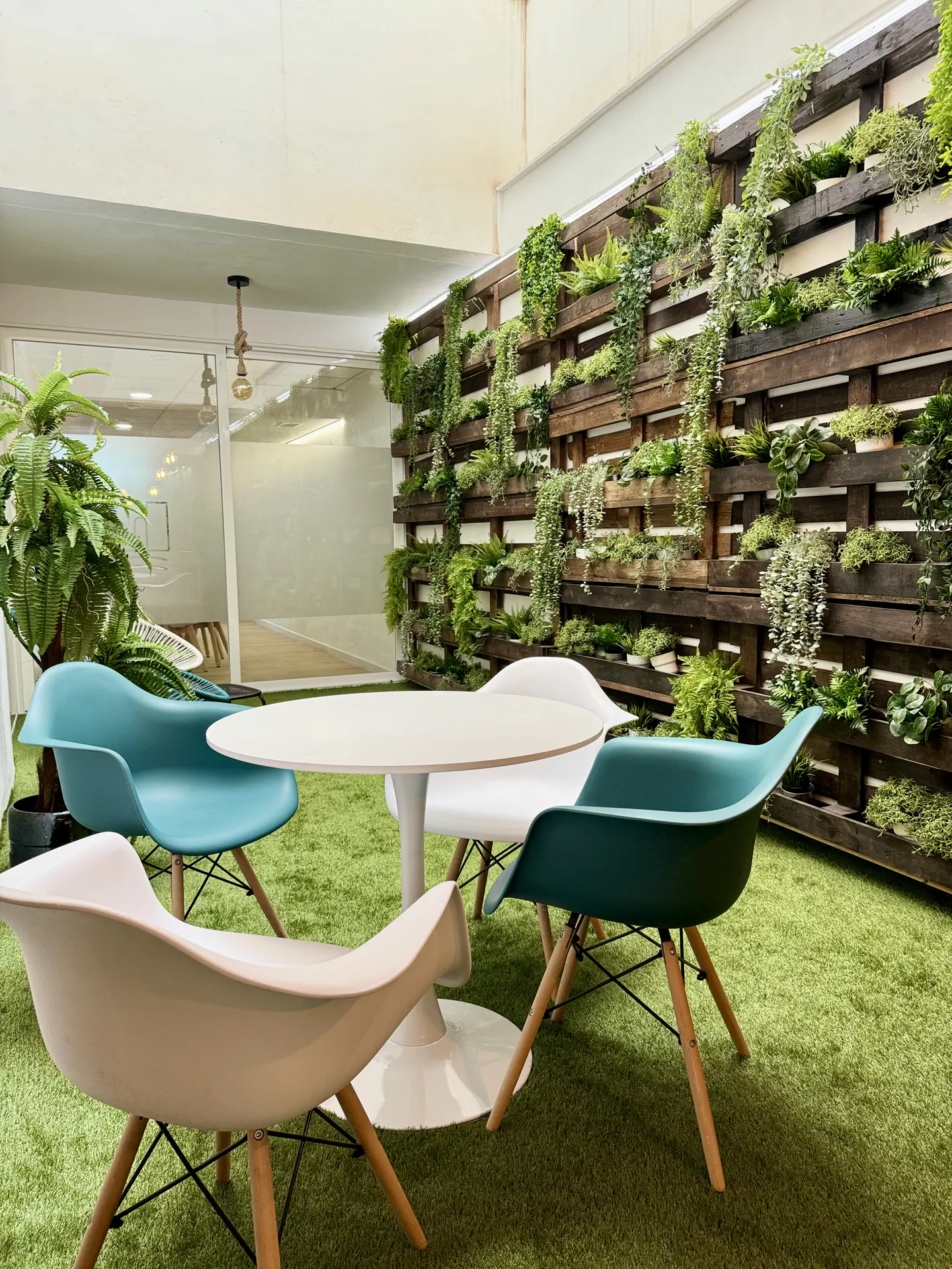 Jardín interior — Un patio interior acristalado con vegetación, luz y asientos para hacer una pausa.